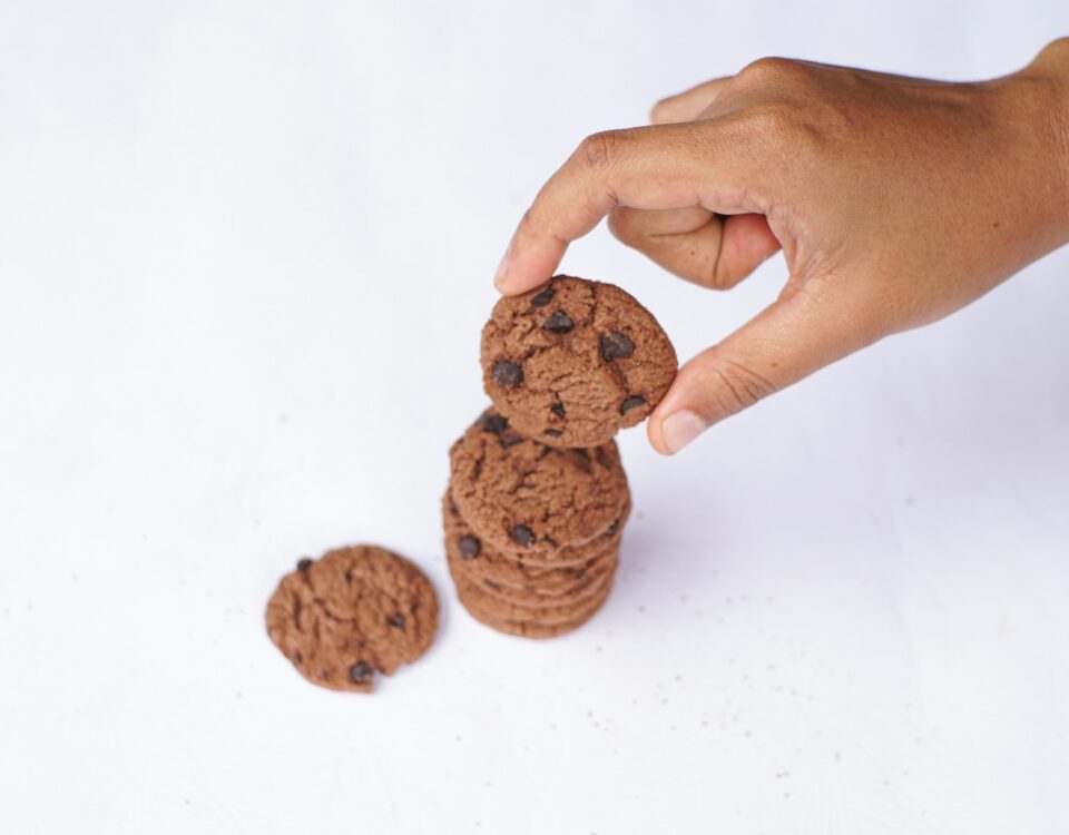 Hand is stacking chocolate chip cookies.